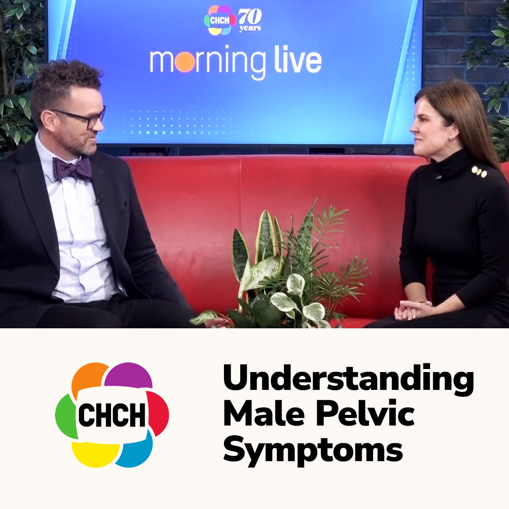 Two individuals seated on a red couch during a live morning show discussing male pelvic symptoms, with plants in the foreground.
